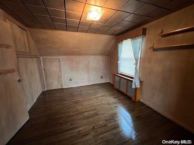 bonus room with lofted ceiling, dark hardwood / wood-style flooring, and wooden walls