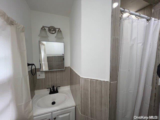 bathroom featuring vanity and tile walls