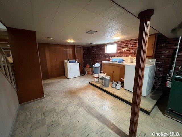 basement with washer / clothes dryer, wooden walls, and brick wall