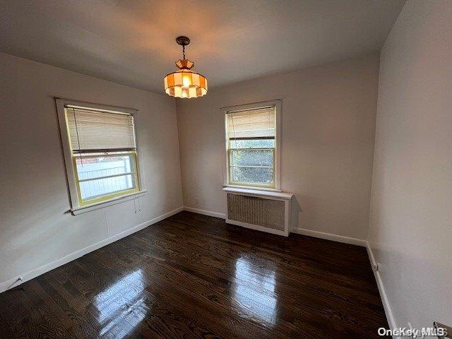 empty room featuring dark wood-type flooring and radiator