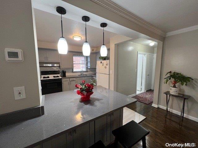 kitchen featuring white appliances, dark wood-type flooring, ventilation hood, sink, and decorative light fixtures