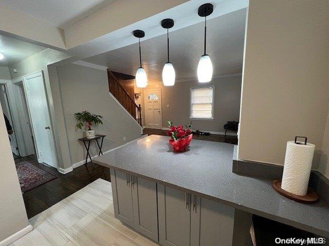 kitchen featuring crown molding, hardwood / wood-style floors, and decorative light fixtures