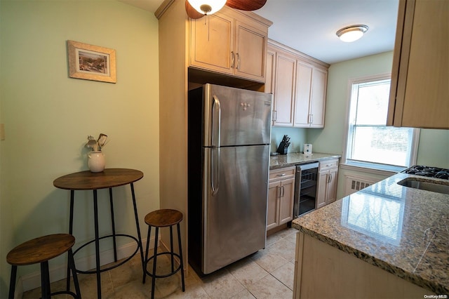 kitchen with light stone countertops, stainless steel fridge, wine cooler, and light brown cabinetry