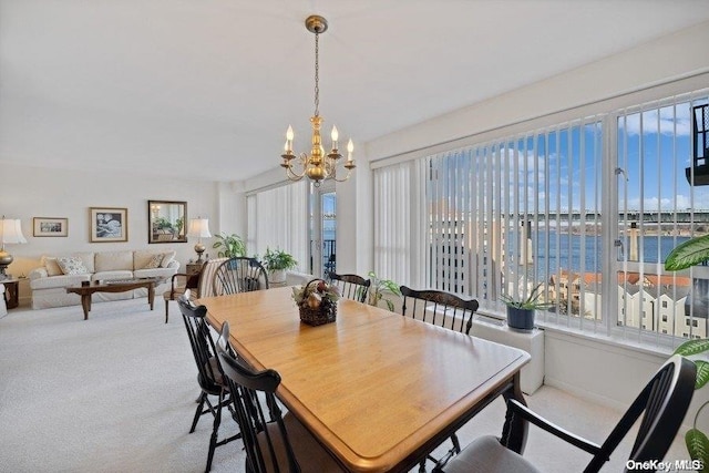 carpeted dining room with a water view, a healthy amount of sunlight, and an inviting chandelier