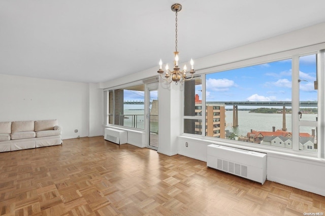 interior space with parquet flooring, radiator heating unit, a water view, and an inviting chandelier