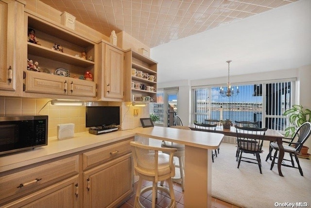 kitchen with kitchen peninsula, decorative backsplash, a breakfast bar, a chandelier, and hanging light fixtures