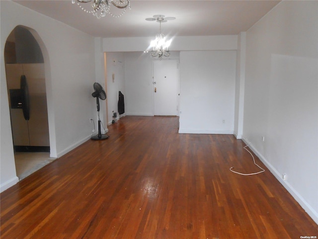 empty room featuring dark hardwood / wood-style floors and an inviting chandelier