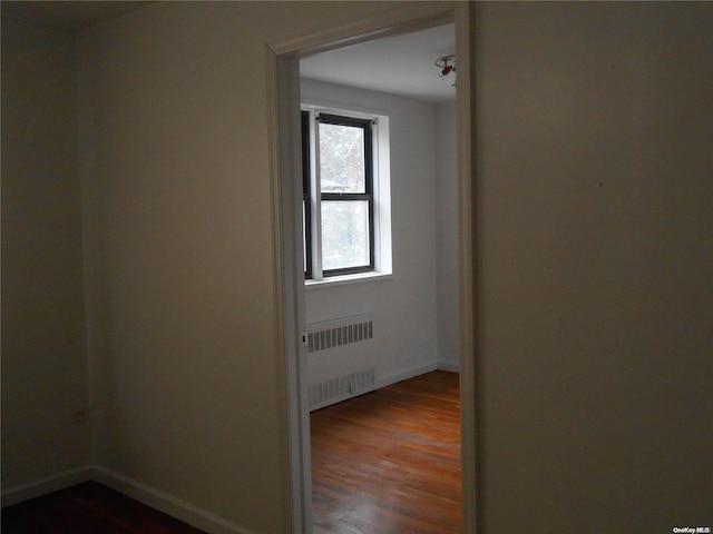 spare room with radiator heating unit and dark hardwood / wood-style flooring