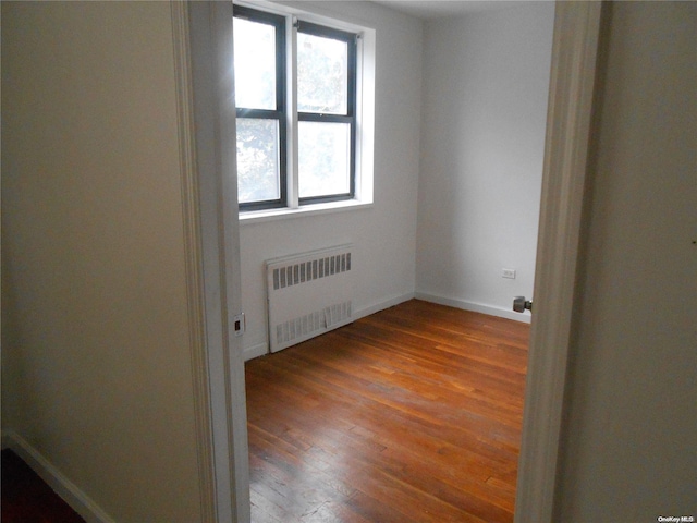 empty room with radiator heating unit and wood-type flooring