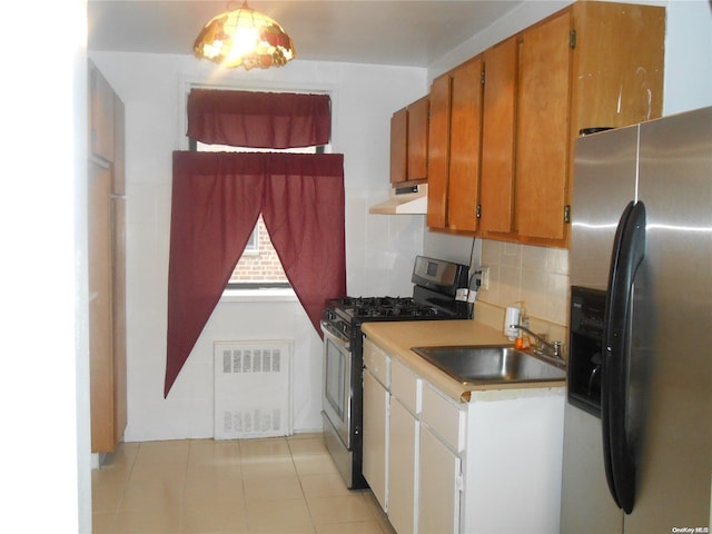 kitchen featuring radiator, sink, decorative backsplash, light tile patterned floors, and stainless steel appliances