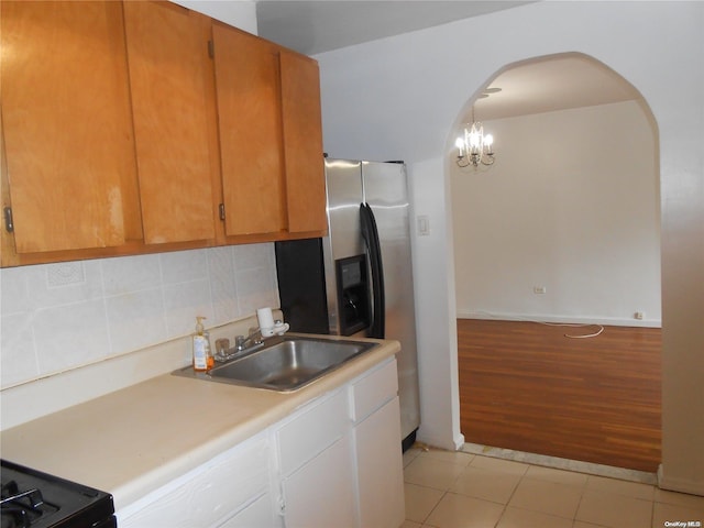 kitchen with pendant lighting, backsplash, sink, a notable chandelier, and light hardwood / wood-style floors