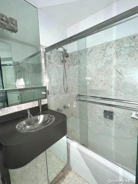 bathroom with enclosed tub / shower combo and sink