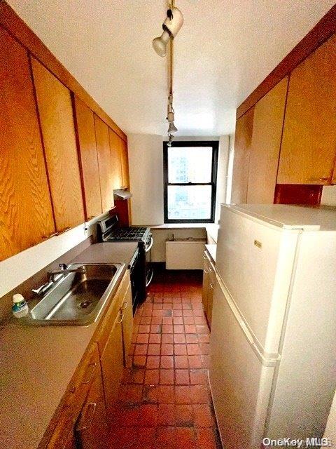 kitchen with gas range, a textured ceiling, white fridge, and sink