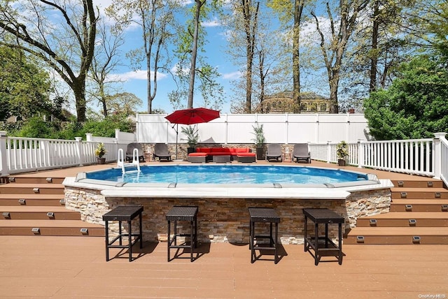 view of pool with outdoor lounge area, a deck, and exterior bar