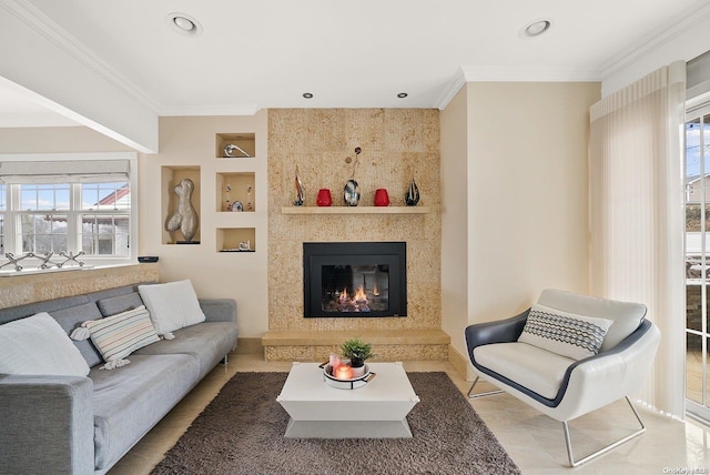 living room featuring a large fireplace, crown molding, built in features, and plenty of natural light