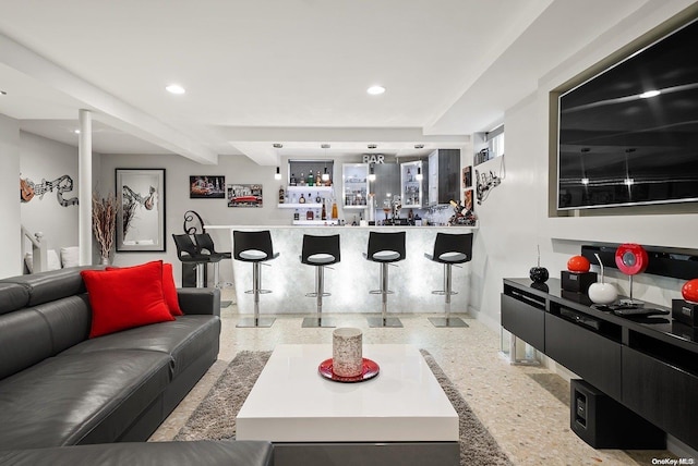 living room featuring beam ceiling and bar area