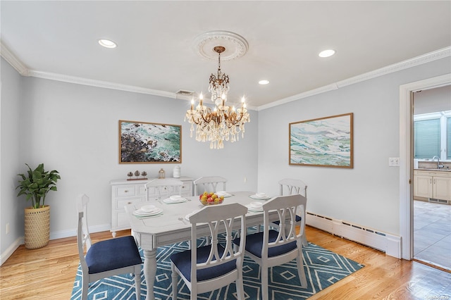 dining area with baseboard heating, light hardwood / wood-style flooring, an inviting chandelier, and sink