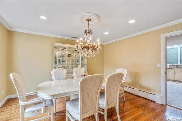 dining area with baseboard heating, crown molding, sink, an inviting chandelier, and hardwood / wood-style floors