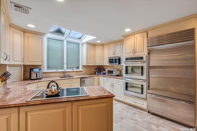 kitchen featuring sink, stainless steel appliances, tasteful backsplash, and a skylight