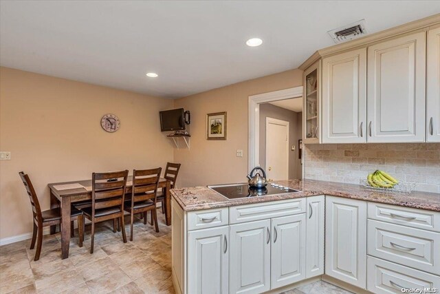 4 Midfarm Rd, Rockville Centre, NY 11570 - kitchen with black electric stovetop, tasteful backsplash, a peninsula, light stone countertops, and glass insert cabinets