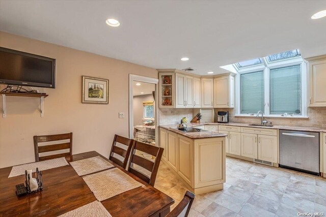 4 Midfarm Rd, Rockville Centre, NY 11570 - kitchen with stainless steel dishwasher, cream cabinets, decorative backsplash, a skylight, and recessed lighting