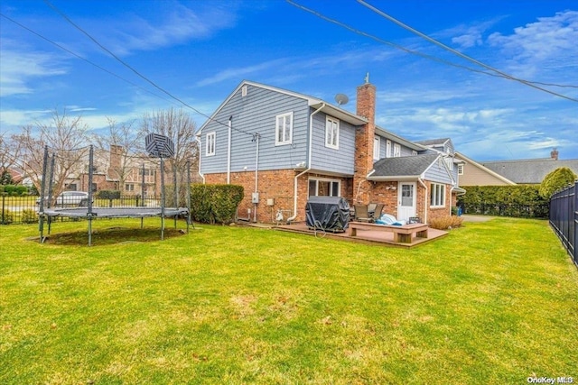 4 Midfarm Rd, Rockville Centre, NY 11570 - back of house featuring a trampoline, a fenced backyard, a deck, brick siding, and a chimney