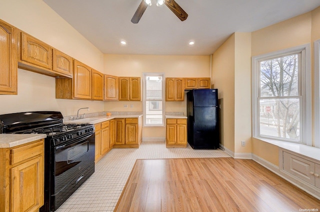 kitchen featuring ceiling fan, light hardwood / wood-style flooring, black appliances, and sink