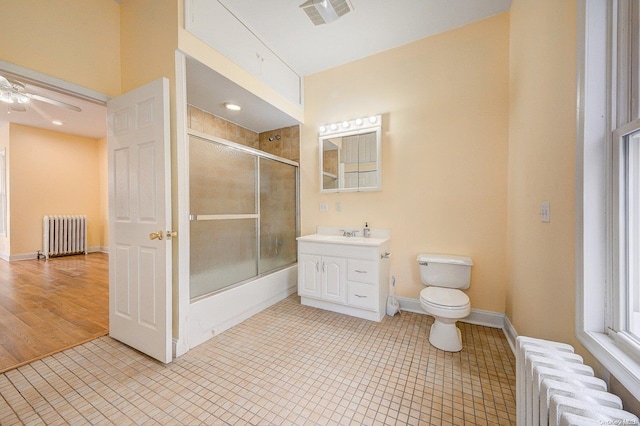 full bathroom featuring bath / shower combo with glass door, radiator heating unit, wood-type flooring, and toilet