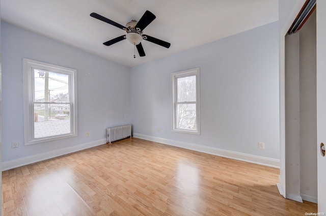 empty room with ceiling fan, radiator heating unit, and light wood-type flooring