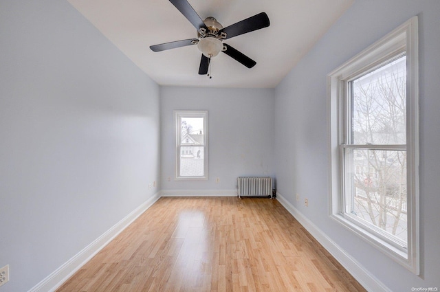 spare room with plenty of natural light, ceiling fan, light wood-type flooring, and radiator