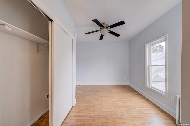 unfurnished bedroom with ceiling fan, light wood-type flooring, radiator heating unit, and a closet