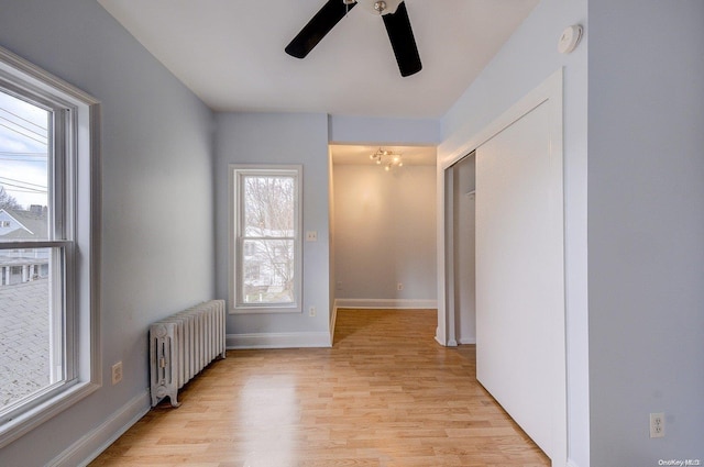 spare room featuring ceiling fan, radiator heating unit, and light hardwood / wood-style flooring