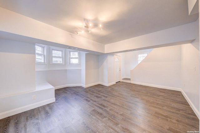 basement featuring plenty of natural light and dark hardwood / wood-style flooring