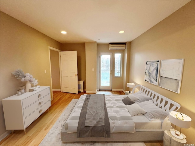 bedroom featuring light hardwood / wood-style floors, a wall unit AC, and access to outside