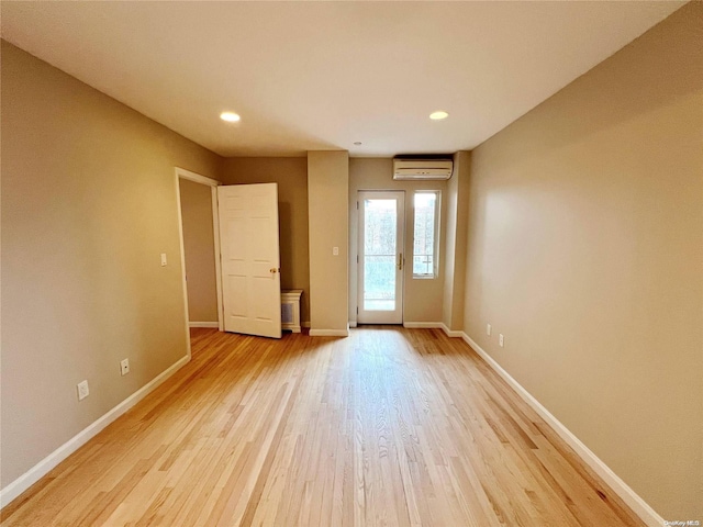 unfurnished room with light hardwood / wood-style floors and a wall mounted AC