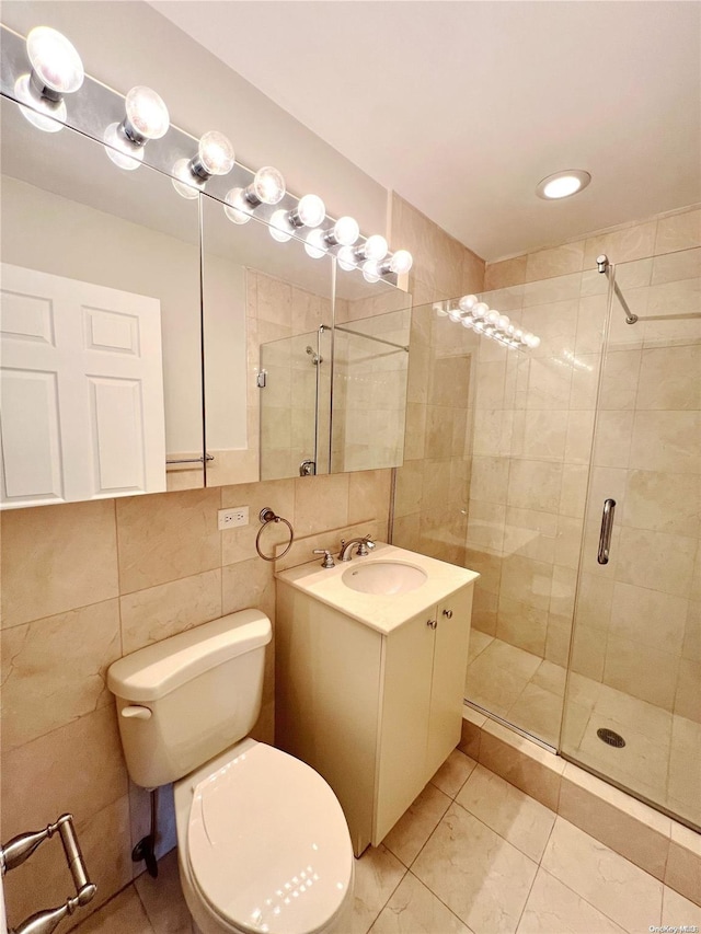 bathroom with tile patterned floors, vanity, tile walls, toilet, and a shower with shower door