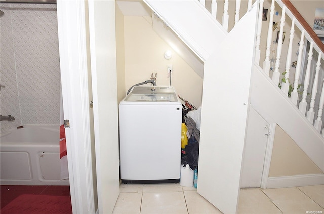 clothes washing area with washer / dryer and light tile patterned floors