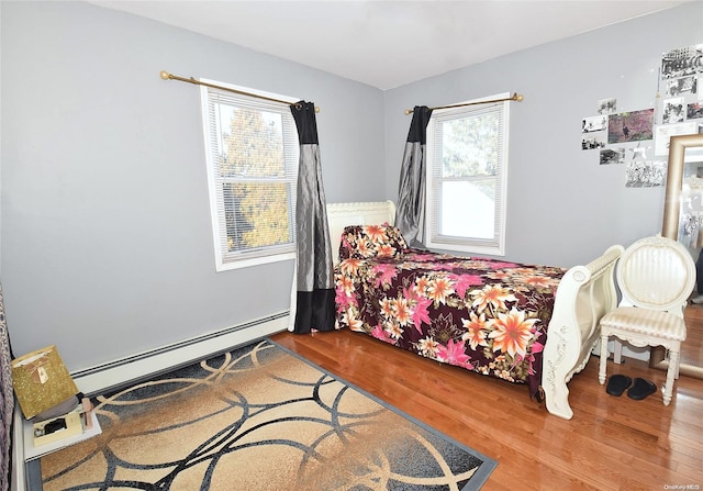 bedroom featuring hardwood / wood-style floors and a baseboard heating unit