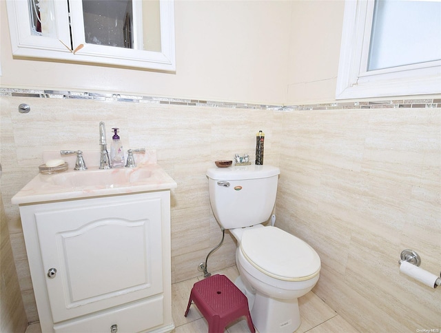 bathroom with tile patterned floors, vanity, toilet, and tile walls