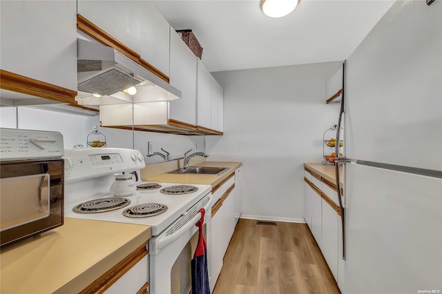 kitchen with white appliances, wall chimney range hood, sink, light hardwood / wood-style floors, and white cabinetry