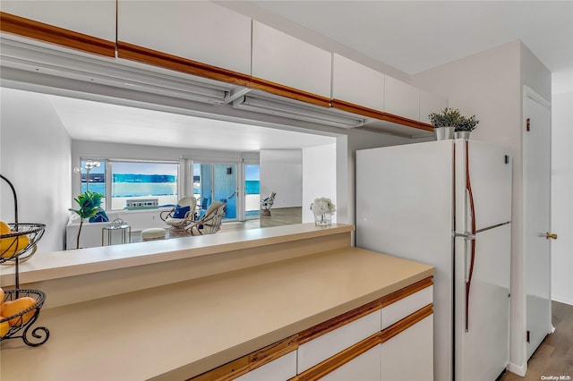 kitchen with hardwood / wood-style floors, white refrigerator, and white cabinetry