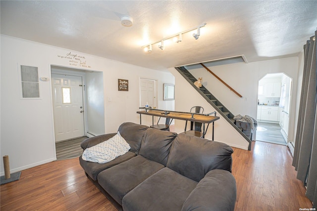 living room with dark hardwood / wood-style floors, baseboard heating, a textured ceiling, and track lighting