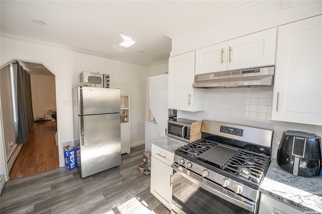 31 William St, Copiague, NY 11726 - kitchen featuring stainless steel appliances, under cabinet range hood, wood finished floors, decorative backsplash, and white cabinets
