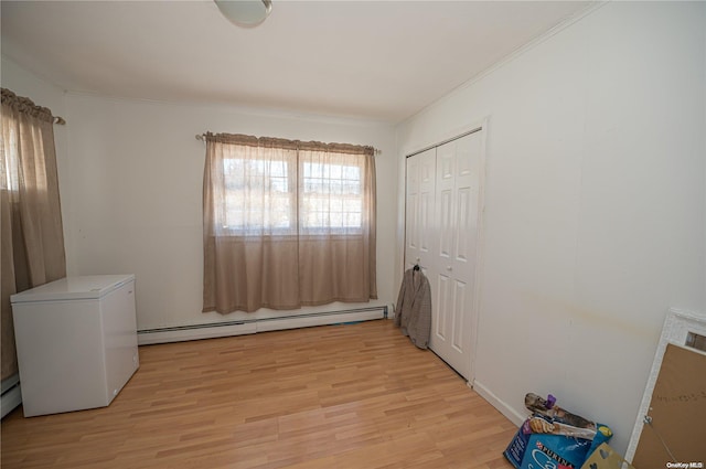 bedroom featuring refrigerator, ornamental molding, a baseboard radiator, light hardwood / wood-style floors, and a closet