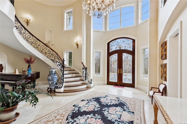 tiled entryway featuring an inviting chandelier, a towering ceiling, and french doors