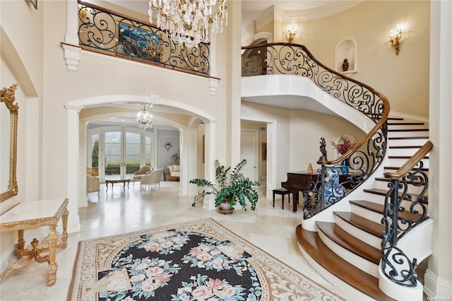 entrance foyer featuring decorative columns, a towering ceiling, and an inviting chandelier