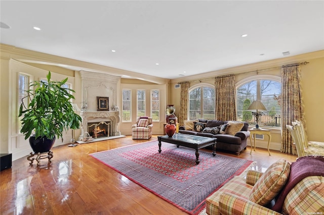 living room with a large fireplace, light hardwood / wood-style flooring, a wealth of natural light, and ornamental molding