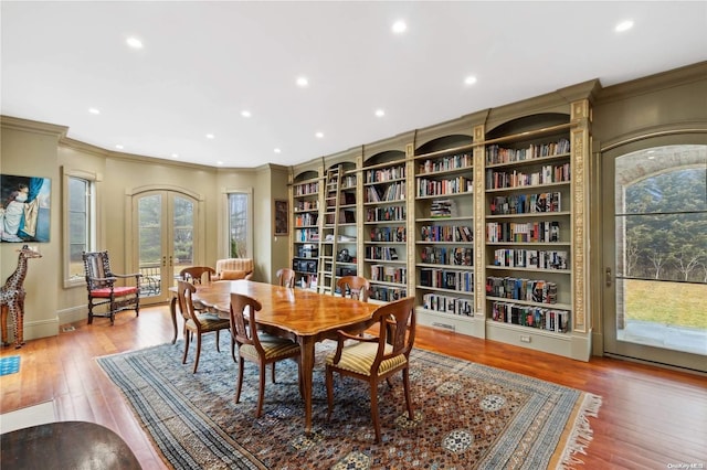 dining space featuring light hardwood / wood-style floors, crown molding, and french doors