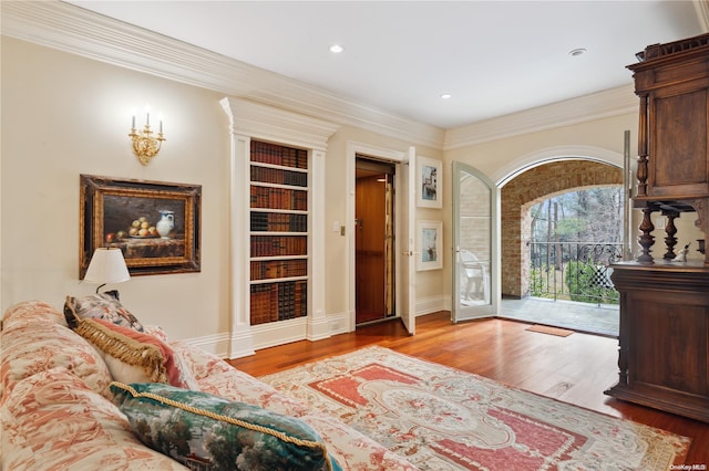 sitting room with built in shelves, light wood-type flooring, and crown molding