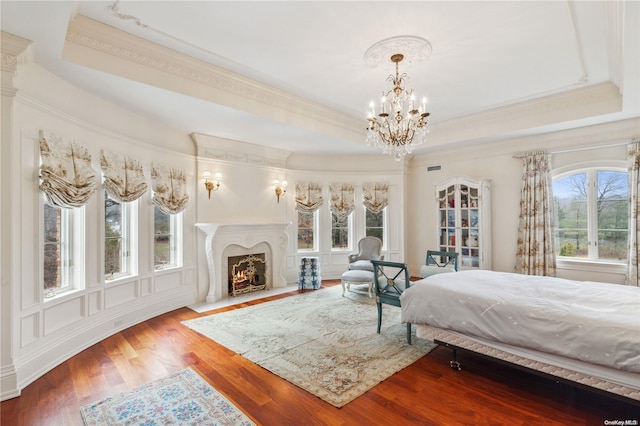 bedroom featuring hardwood / wood-style flooring, a notable chandelier, a raised ceiling, and crown molding